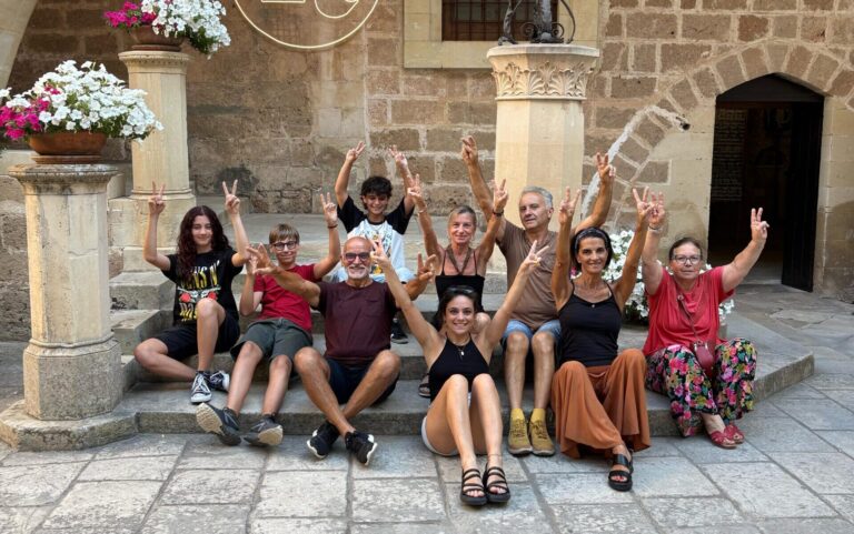 nove persone sedute sulla scale dell'atrio del castello con le braccia in su